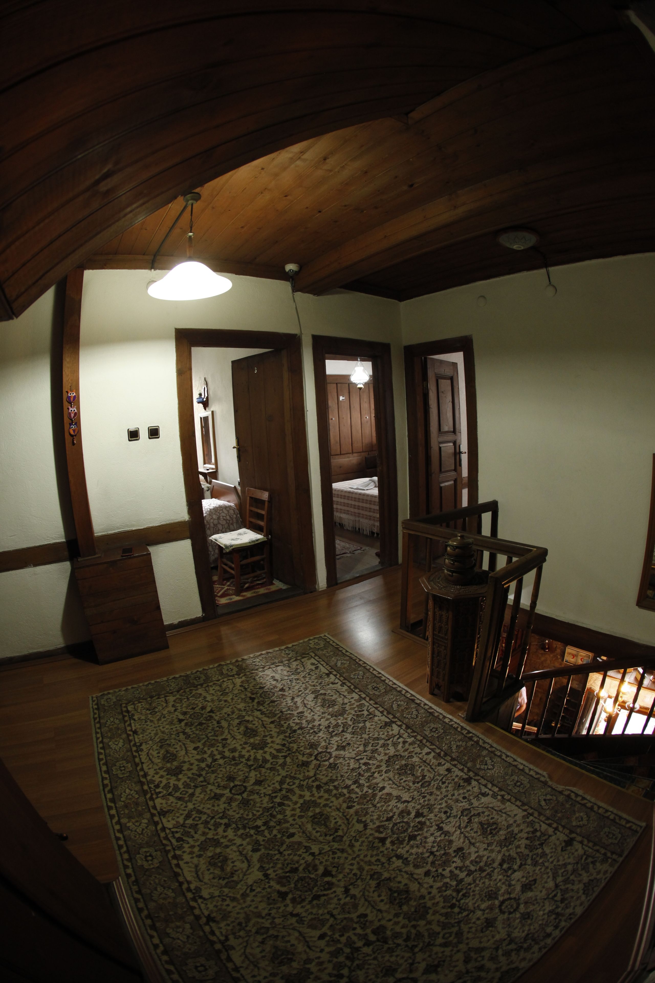 Ein geräumiges Loft mit hohen Decken, Holzbalken, einem großen, gemusterten Teppich und einer Treppe, die in eine erhöhte Ebene führt.
