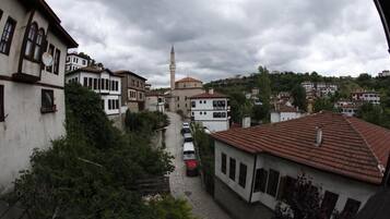 A narrow street with buildings on either side, a mosque with a minaret, and parked cars.