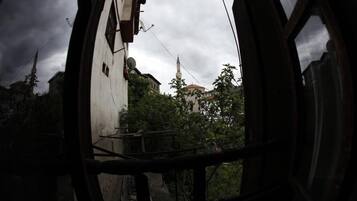A view through a window with a metal frame, looking out at a building with a pointed roof and a tower.