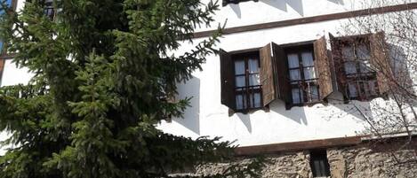 A building with a stone facade and wooden shutters on the windows.