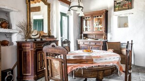 Een eetkamer met een houten tafel, stoelen, een kroonluchter en een grote spiegel.