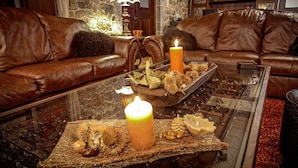 A cozy living room with leather sofas, a glass coffee table with candles, and a stone wall. - Xenonas Ouranogiton (South Kynouria)