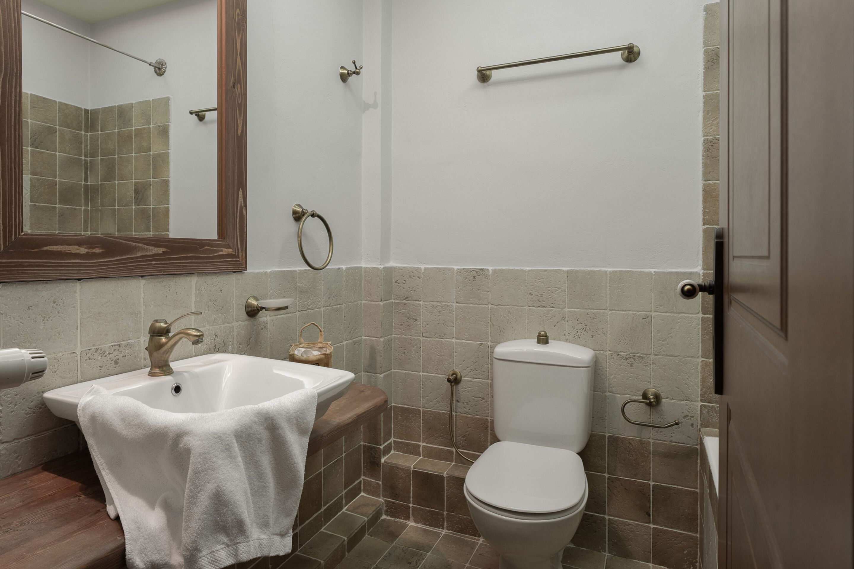 A bathroom with a sink, toilet, and a mirror.