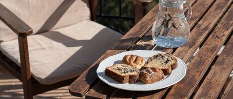 A wooden table with a plate of pastries and a glass pitcher.