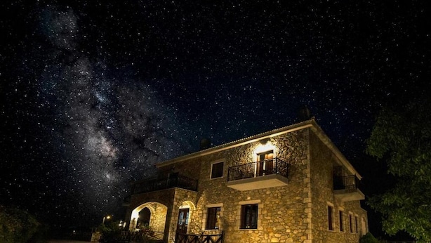 A stone building with a balcony, under a starry night sky. - Xenonas Ouranogiton (South Kynouria)
