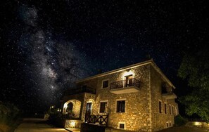 A stone building with a balcony, under a starry night sky. -  Xenonas Ouranogiton (South Kynouria)