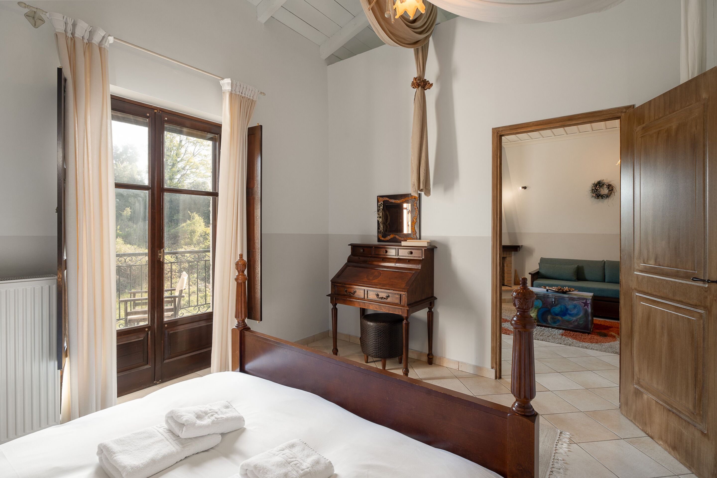 Un dormitorio con una cama grande, un aparador de madera, un espejo y vistas al exterior a través de una ventana.