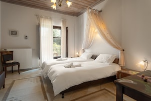 Un dormitorio con dos camas, una silla, una mesa y un ventanal con cortinas.