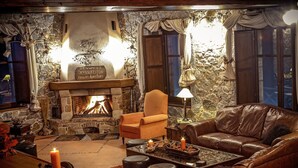A cozy room with a stone fireplace, leather furniture, and a lit candle. - Xenonas Ouranogiton (South Kynouria)