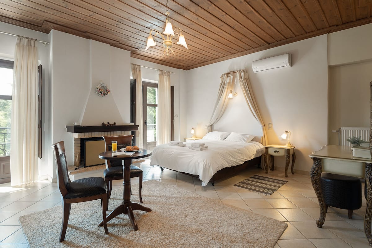 Quarto com cama, mesas de cabeceira, escrivaninha e uma cadeira.