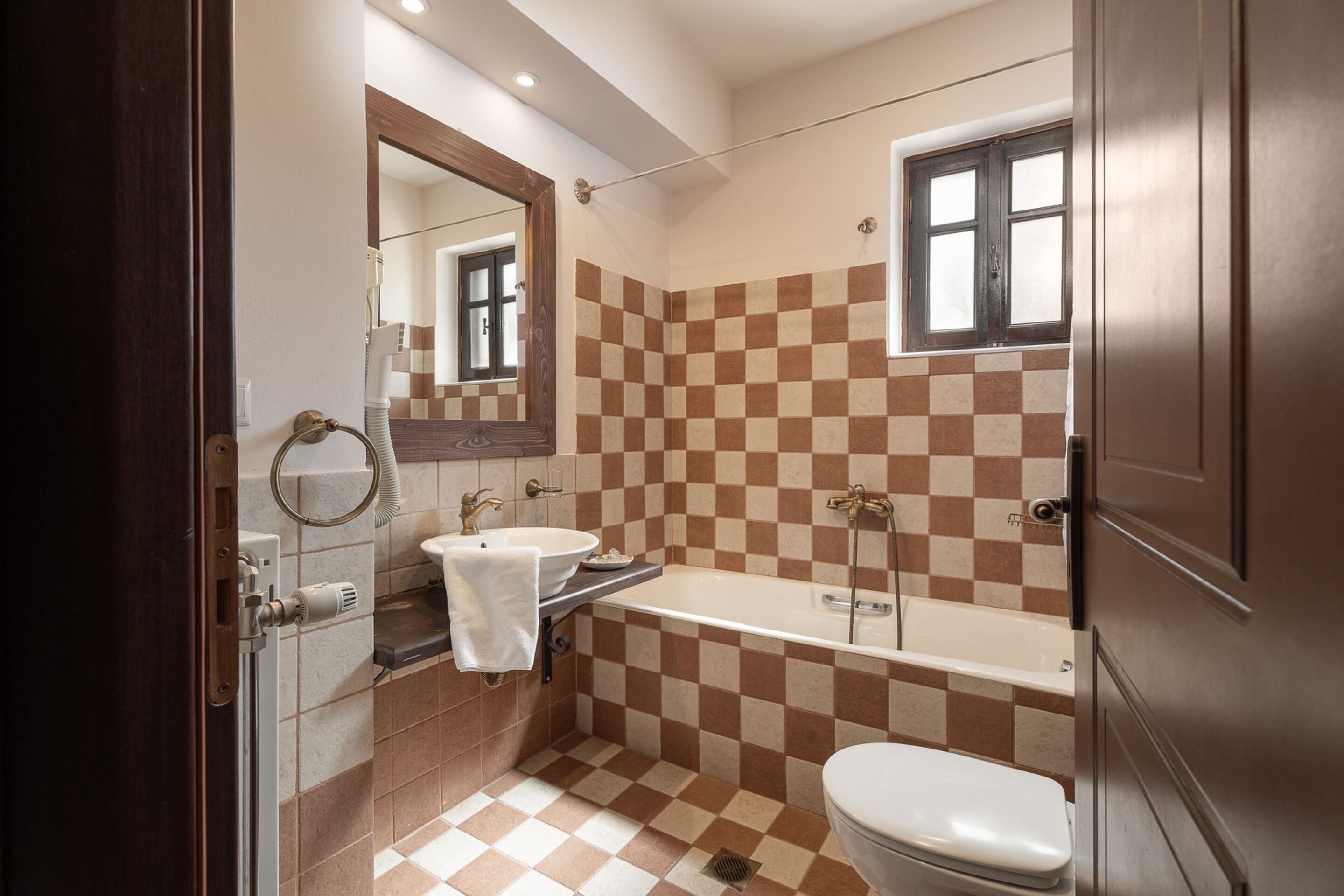 Een badkamer met een vloer van zwart-witte tegels, een wastafel, een bad en een toilet.