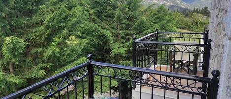 Een balkon met uitzicht op een dicht bos en bergen.