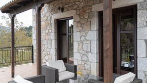 A covered outdoor seating area with wicker furniture and stone walls. - Xenonas Ouranogiton (South Kynouria)