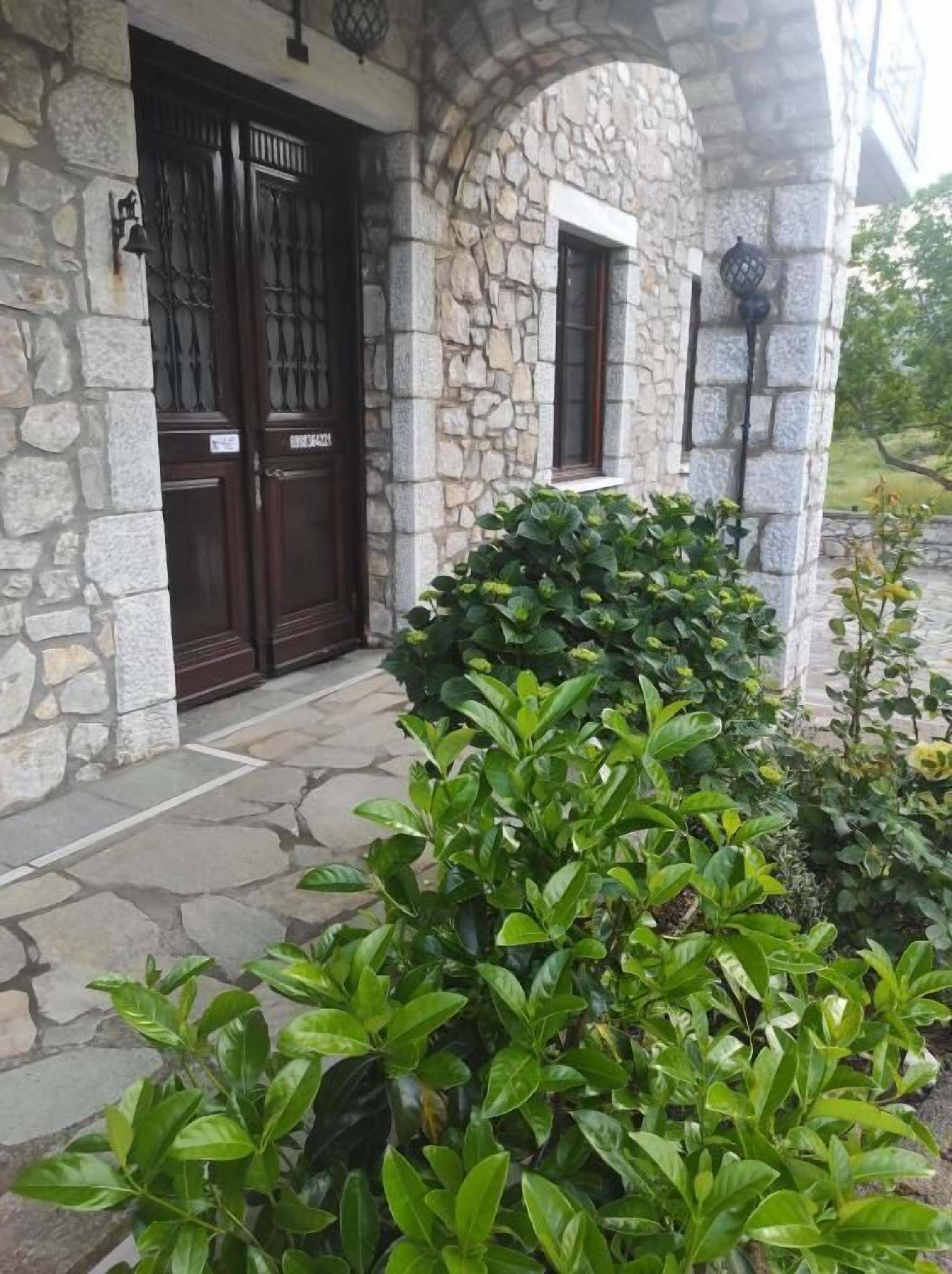 Un edificio de piedra con dos grandes puertas de madera y un ventanal pequeño.