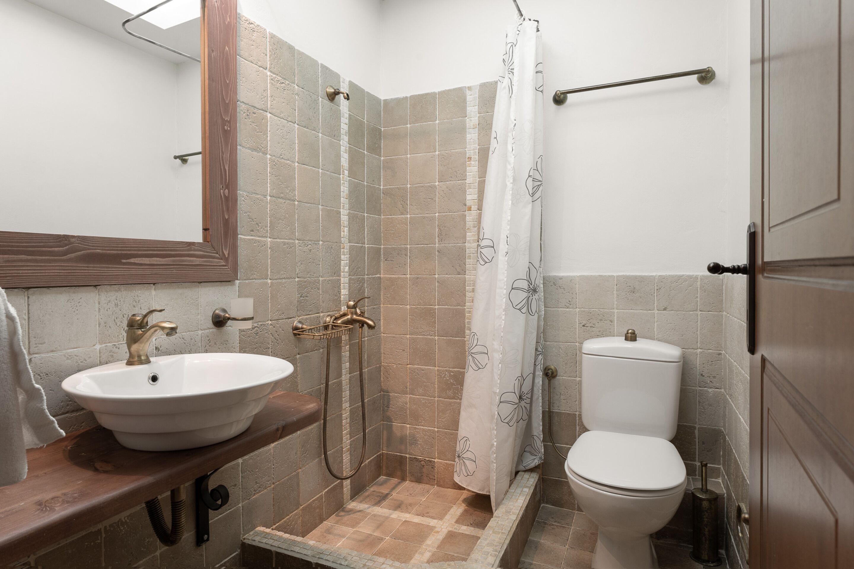 Een badkamer met een wastafel, toilet, douche en een houten wastafelmeubel.