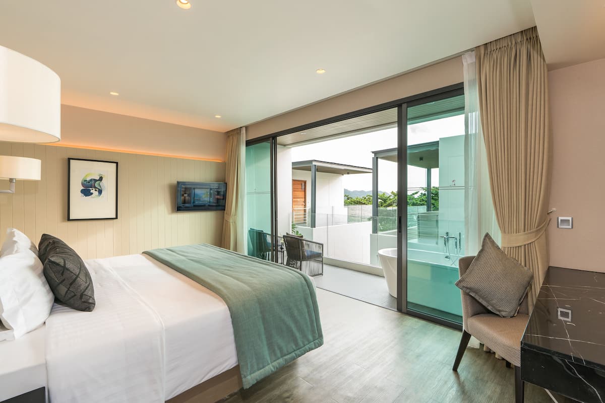 Une chambre d’hôtel moderne comprenant un lit, un coin salon avec vue et une salle de bain avec baignoire.