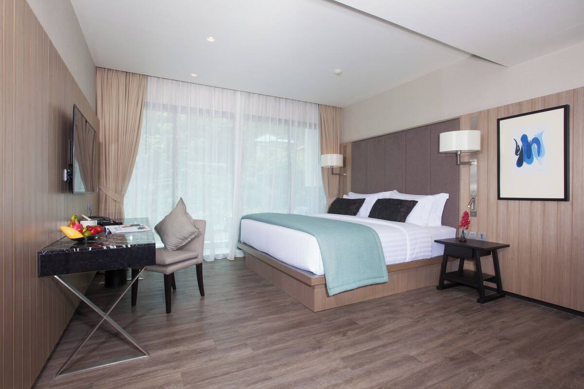 Une chambre d’hôtel moderne équipée d’un lit, d’un bureau, d’une chaise et d’une grande fenêtre avec des rideaux.