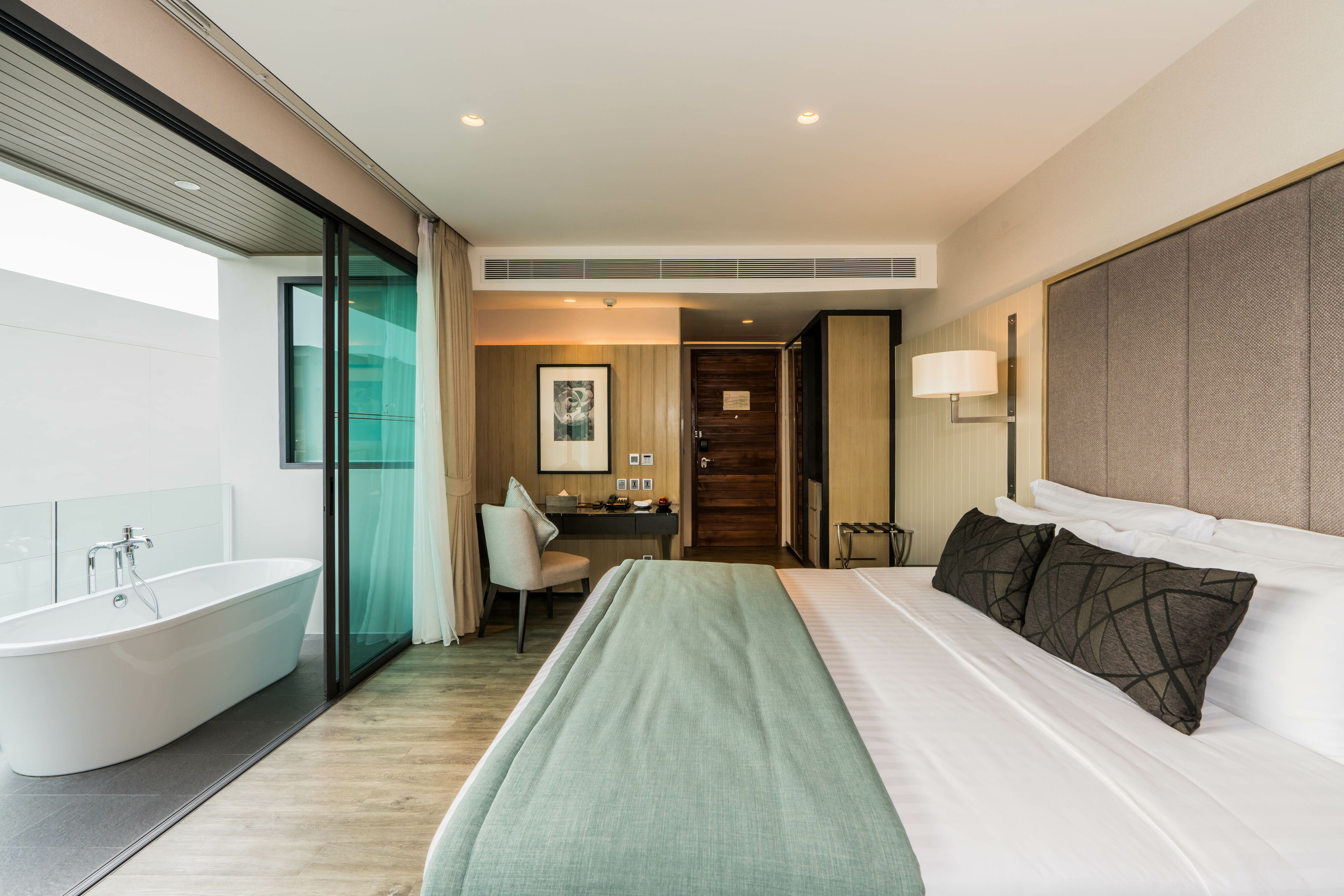 Quarto de hotel moderno com uma cama grande, banheiro separado e uma área de trabalho.