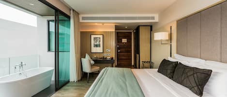 Quarto de hotel moderno com uma cama grande, banheiro separado e uma área de trabalho.