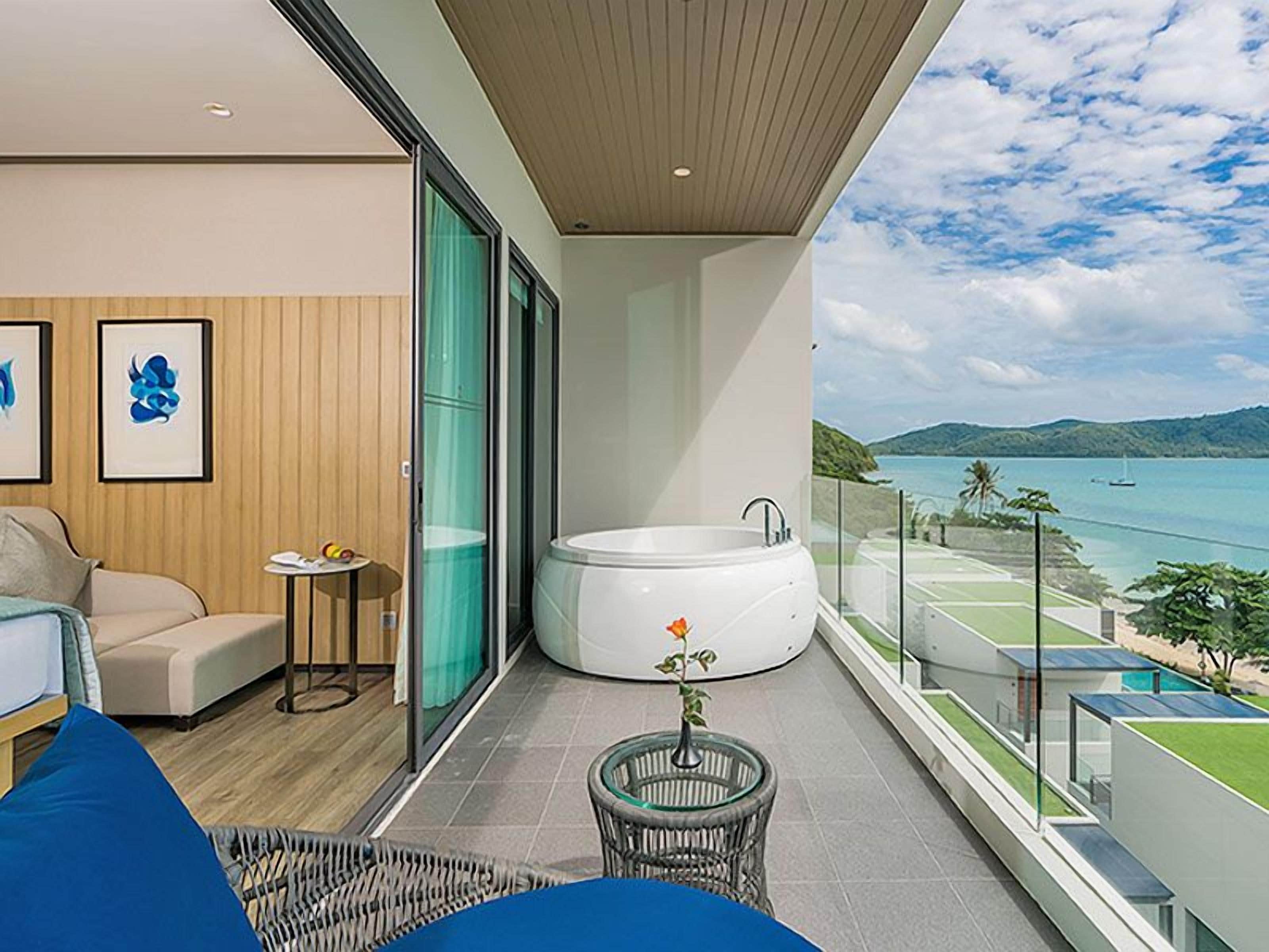 Ein Balkon mit Whirlpool, eine Sitzecke mit einer Couch und Sesseln sowie Meerblick.