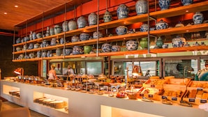A buffet area with a variety of food items and a display of blue and white porcelain vases on shelves. - My Beach Resort Phuket (Wichit)