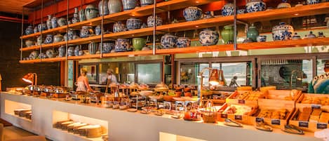 A buffet area with a variety of food items and a display of blue and white porcelain vases on shelves.