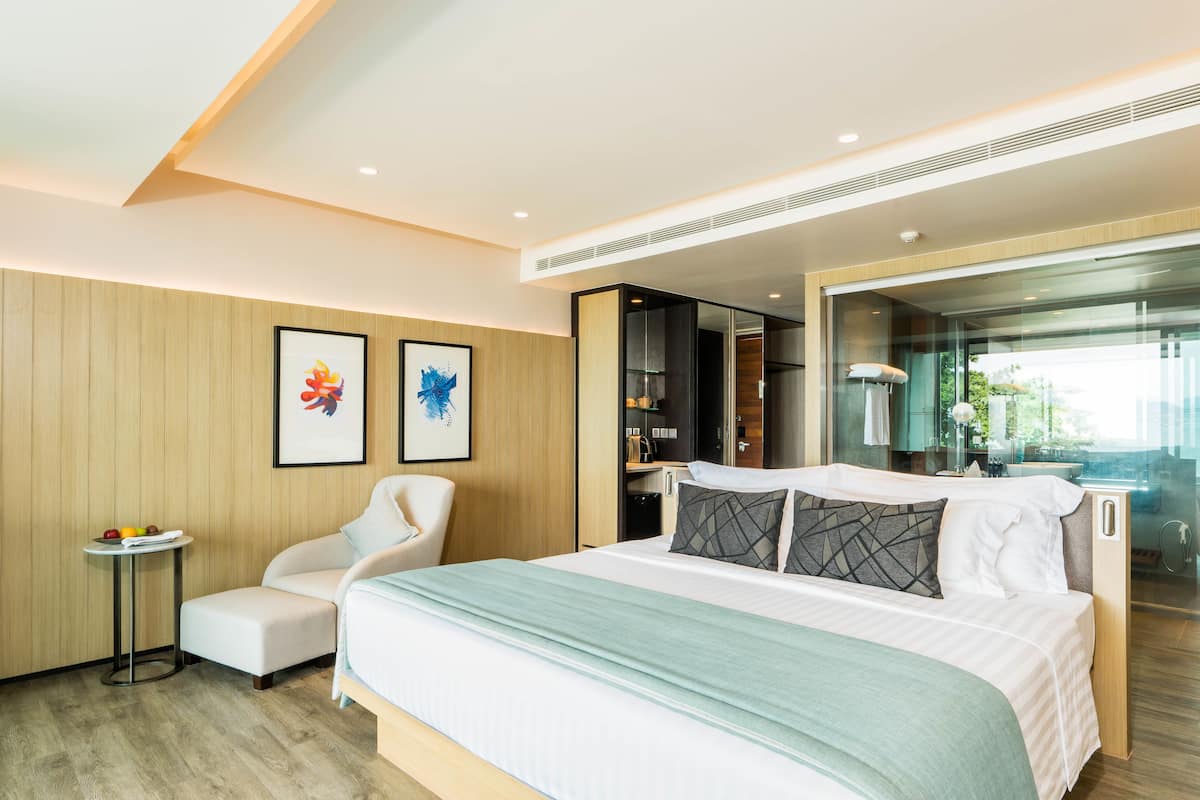 Une chambre d’hôtel moderne équipée d’un lit, d’un coin salon, d’une petite table et d’œuvres d’art accrochées au mur.