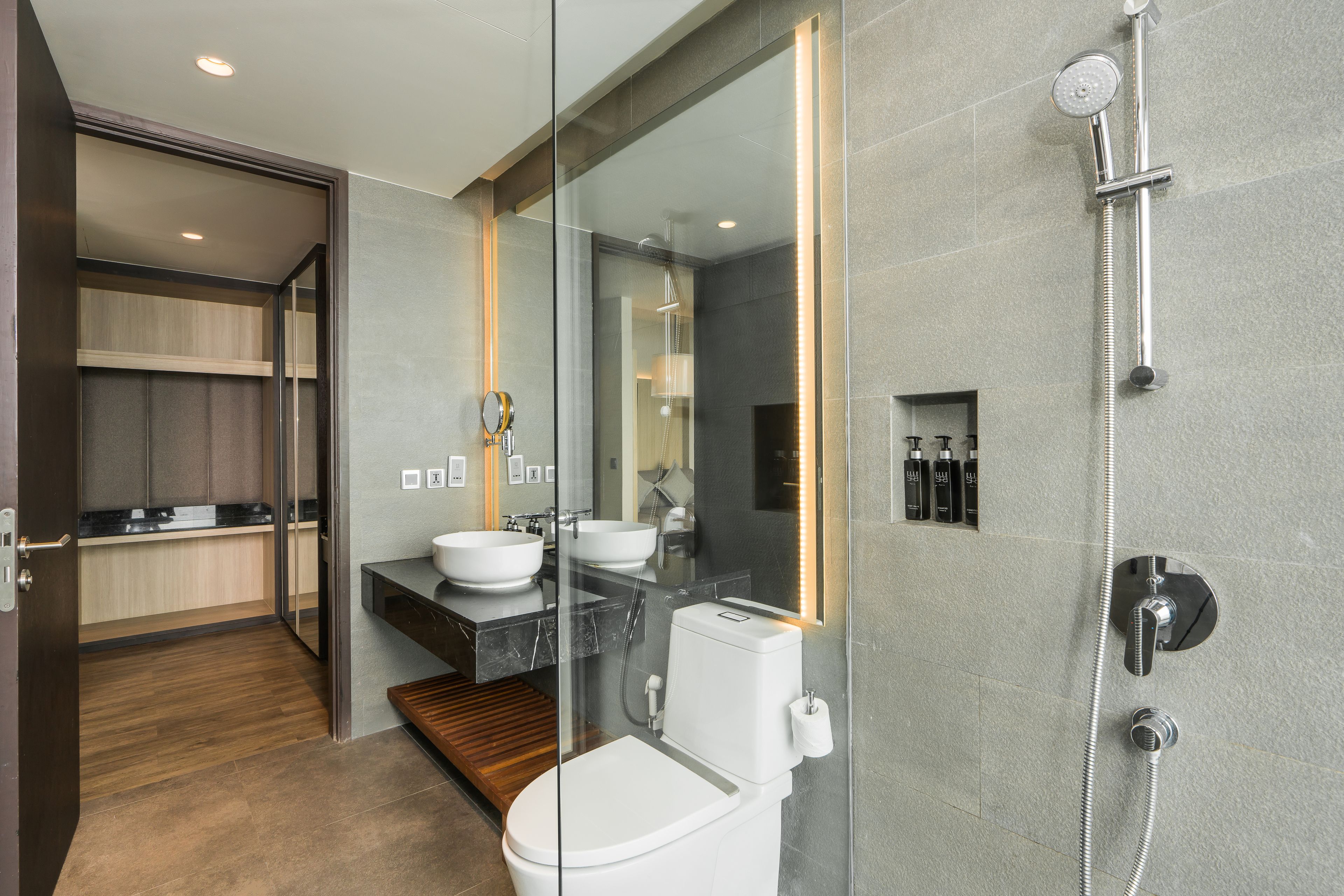 Un baño moderno con cabina de ducha de vidrio, inodoro blanco y tocador con lavamanos y espejo.
