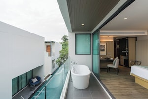 A modern bathroom with a freestanding bathtub, a glass-enclosed pool, and a seating area with a cushion.