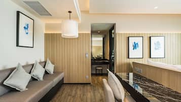 Une chambre d’hôtel moderne avec un mur lambrissé en bois, un canapé avec des coussins, un comptoir en marbre et des œuvres d’art encadrées.