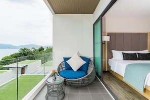 A balcony with a wicker chair, a small table with a vase, and a bed with a headboard. - My Beach Resort Phuket (Wichit)
