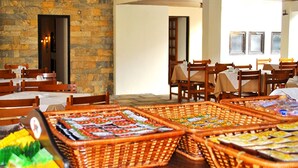 Un comedor con cestas de mimbre llenas de alimentos, mesas y sillas de madera.