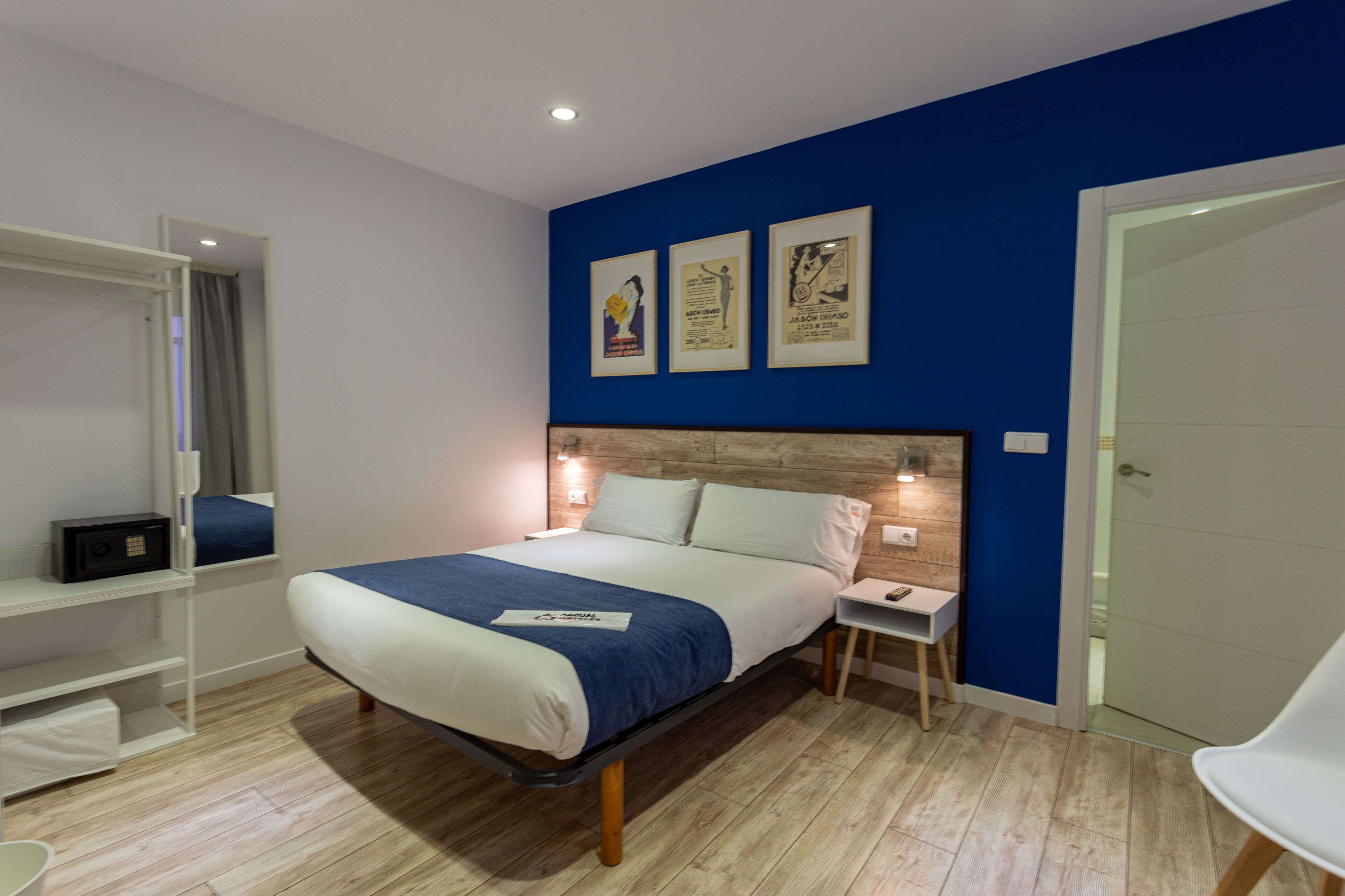 A modern bedroom with a bed, bedside tables, a wardrobe, and a door.