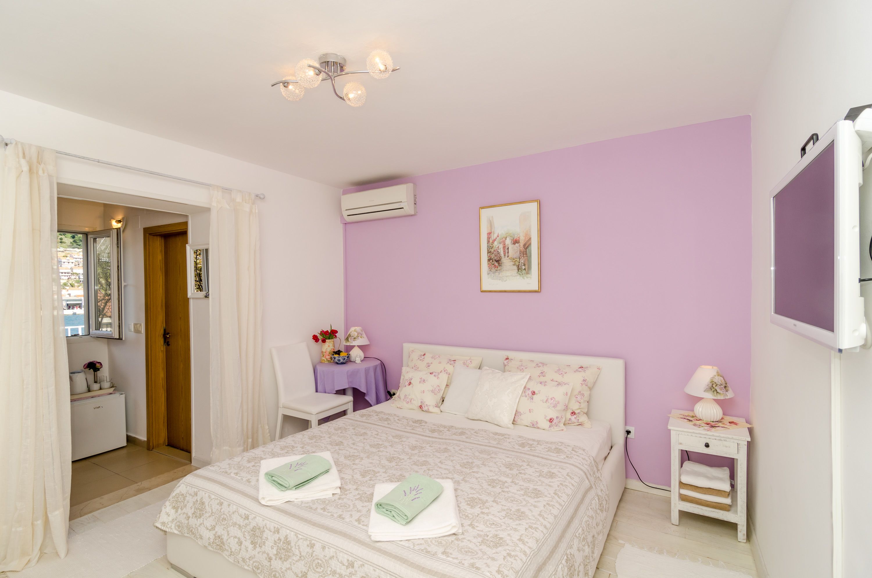 Een slaapkamer met een bed, nachtkastje, raam en een airconditioning.