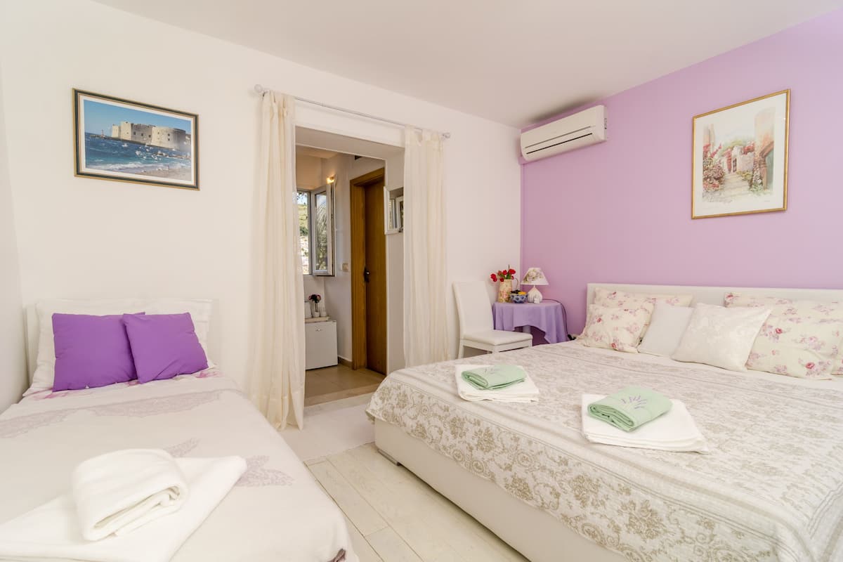 Quarto de hotel com duas camas, banheiro e vista para o mar.