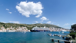 A large cruise ship docked at a harbor with a cityscape and hills in the background. - Guest House Cuk (Dubrovnik)