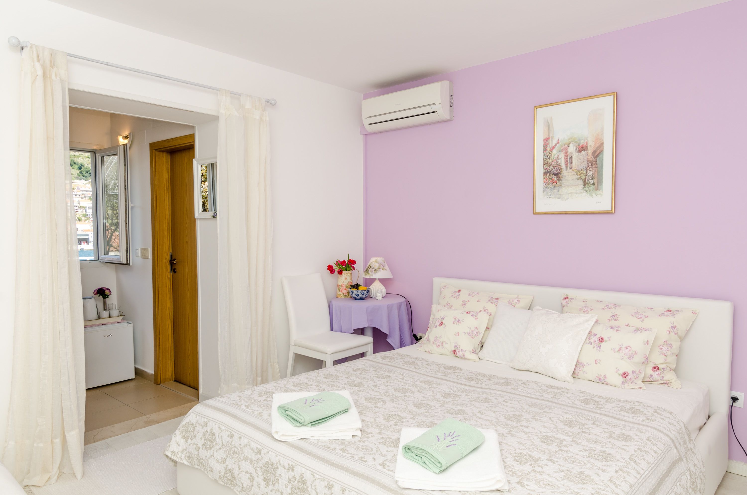 Quarto com uma cama, uma cadeira, uma mesa com abajur e um quadro na parede.