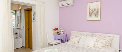 Quarto com uma cama, uma cadeira, uma mesa com abajur e um quadro na parede.