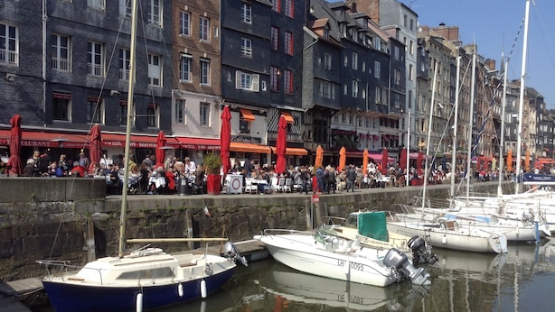 A waterfront area with boats docked, a crowd of people, and buildings with outdoor seating. - La Maison du Phare B&B (Honfleur)