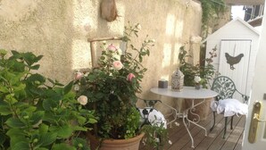 A wooden deck with a white table and chairs, surrounded by potted plants and flowers. - La Maison du Phare B&B (Honfleur)