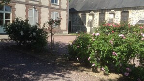 A building with a stone facade, a bell tower, and a gravel courtyard with flowering bushes. - La Maison du Phare B&B (Honfleur)