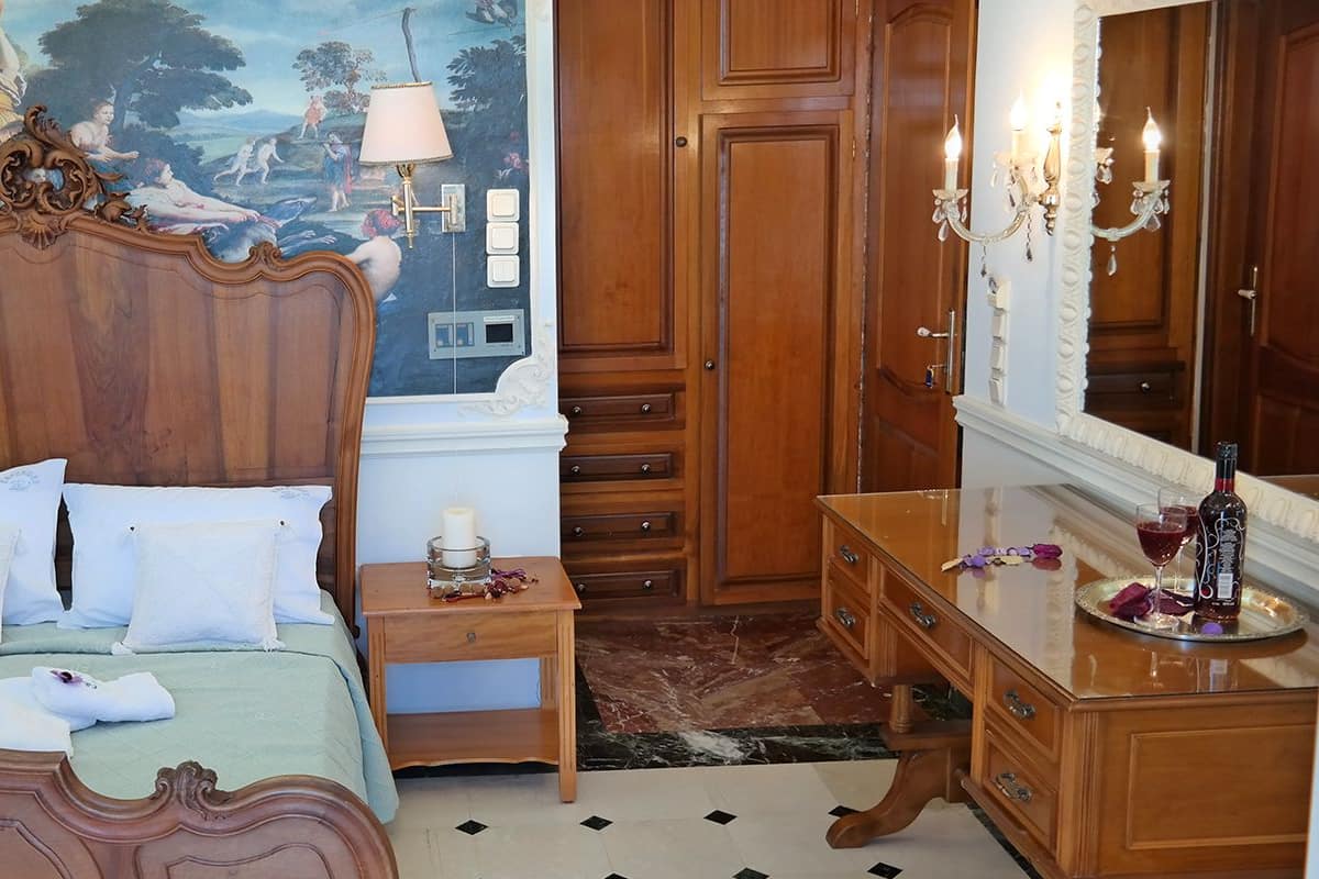 A bedroom with a large bed, wooden headboard, and a mural on the wall.