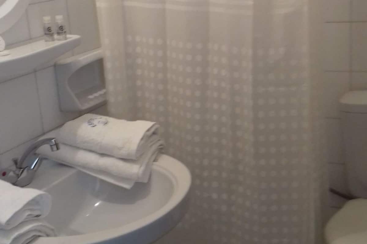 A bathroom with a white sink, a toilet, and a shower curtain.
