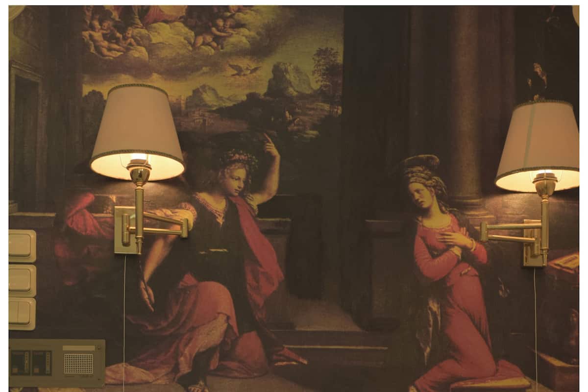 A hotel room with a bed, a lamp, and a painting on the wall.