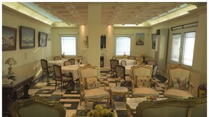 A dining room with ornate chairs, tables, and a checkered floor. - Hotel Esperides (Naxos)