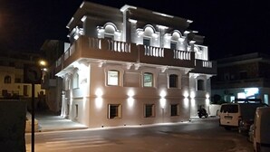 A two-story building with a balcony and multiple windows, illuminated by exterior lights. - Hotel Esperides (Naxos)