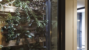 A wooden wall with various plants and a glass door. - City Stays Bica Apartments (Lisbon)