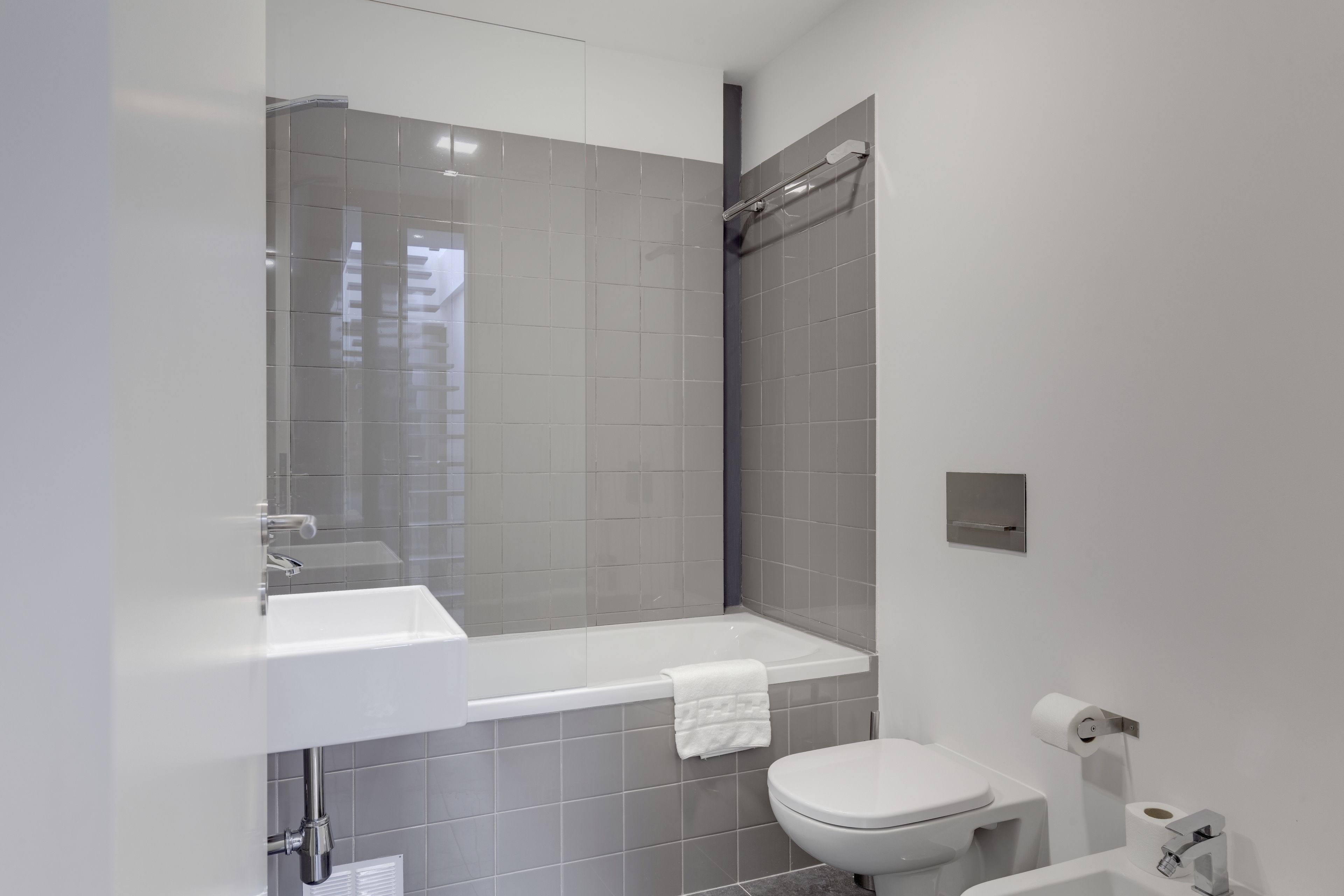 Une salle de bain moderne avec un lavabo, des toilettes et une baignoire, le tout de couleur blanche.