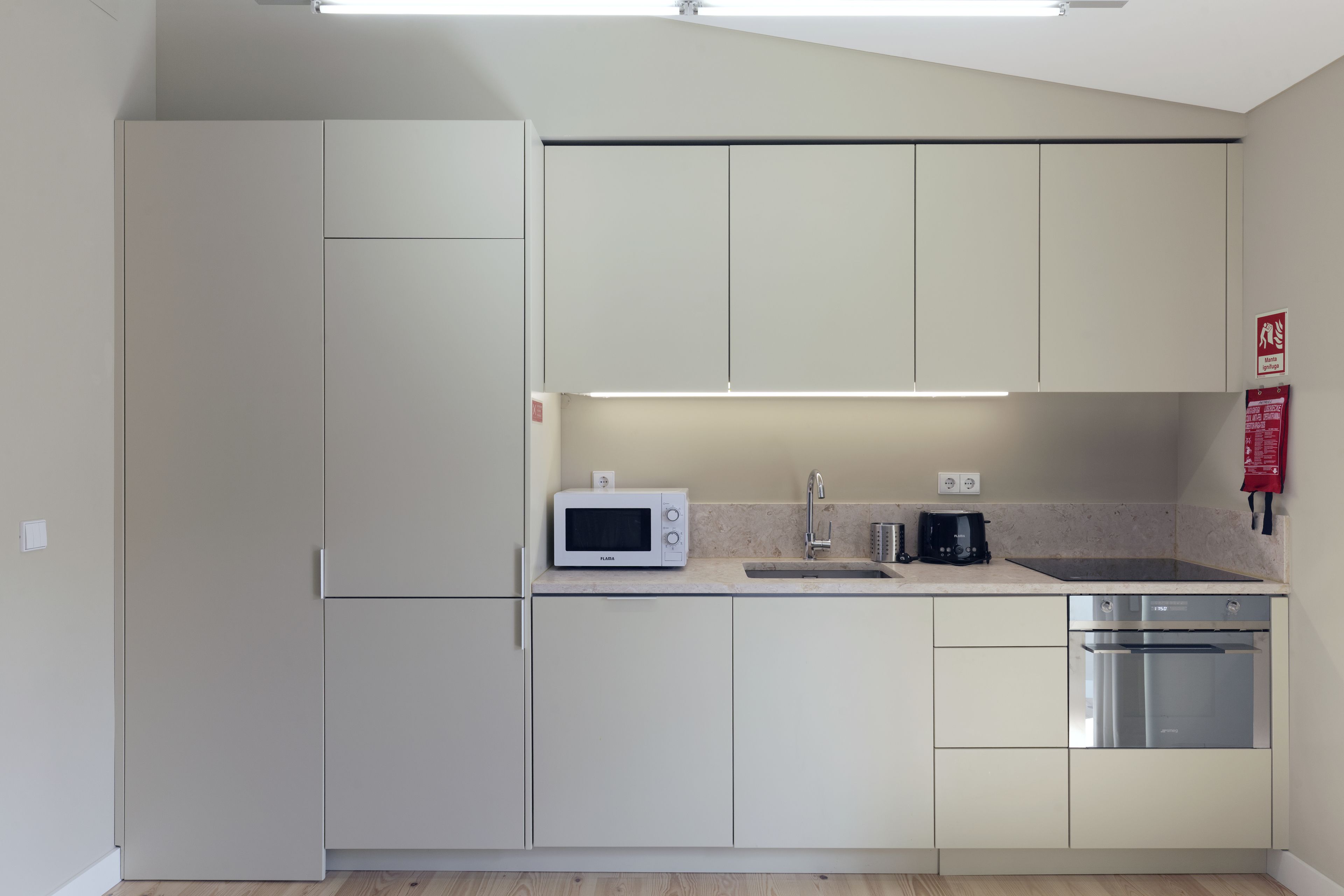 A compact kitchen with white cabinets, a microwave, a coffee maker, a sink, and a dishwasher.