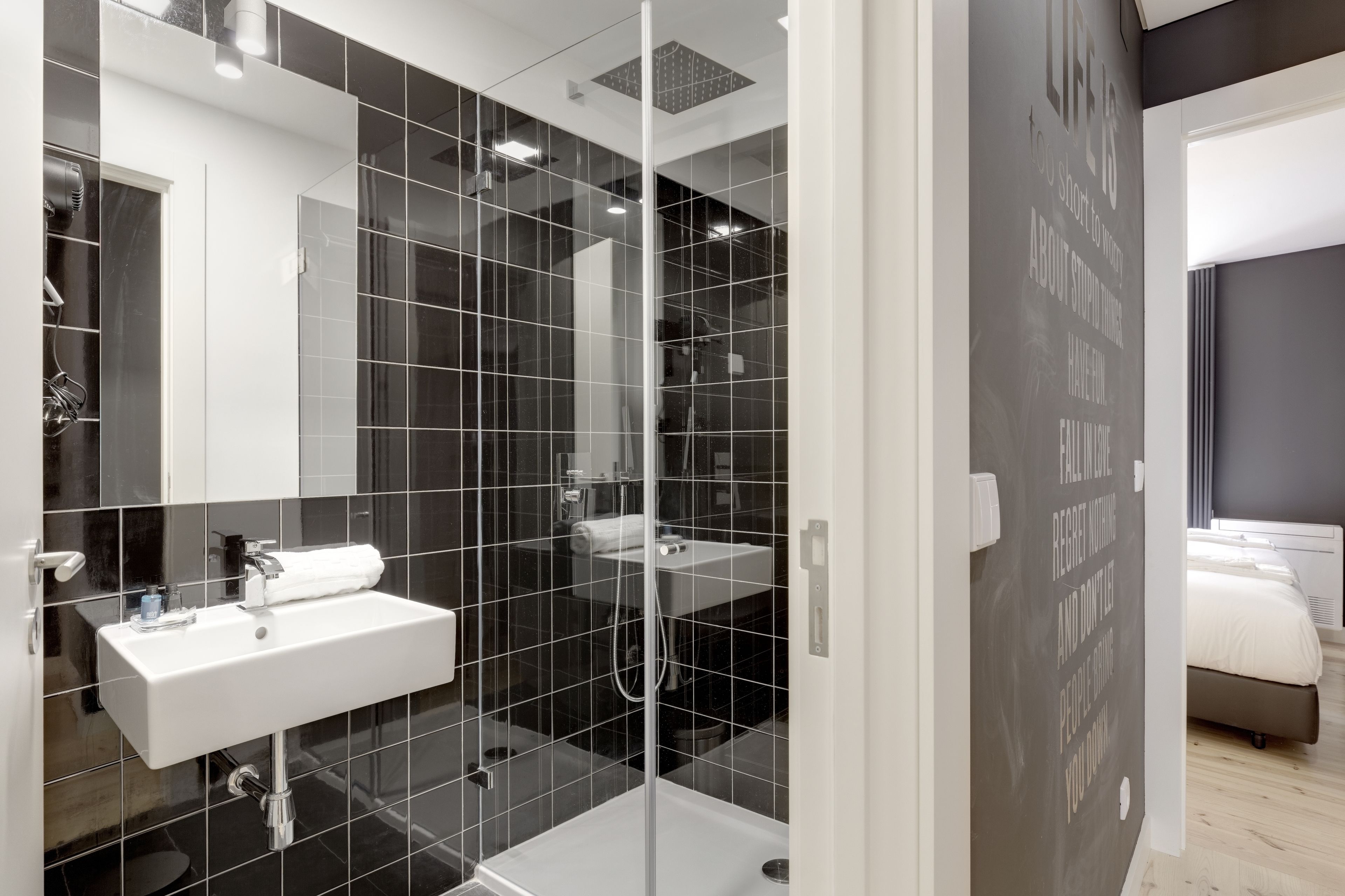 Un baño moderno con ducha envuelta en vidrio, un lavabo blanco y un espejo grande.